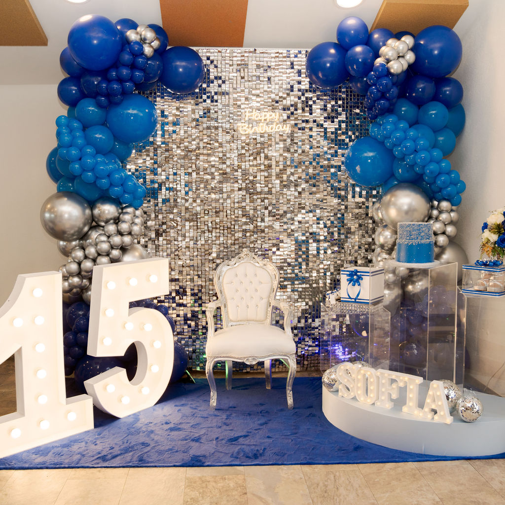 Montaje decorativo de fiesta de quinceañera con pared de lentejuelas y globos azules