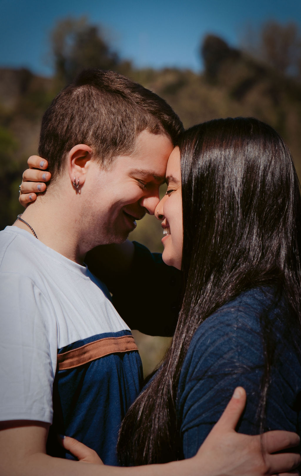 Retrato cercano de una pareja riendo con las frentes juntas durante su sesión de preboda
