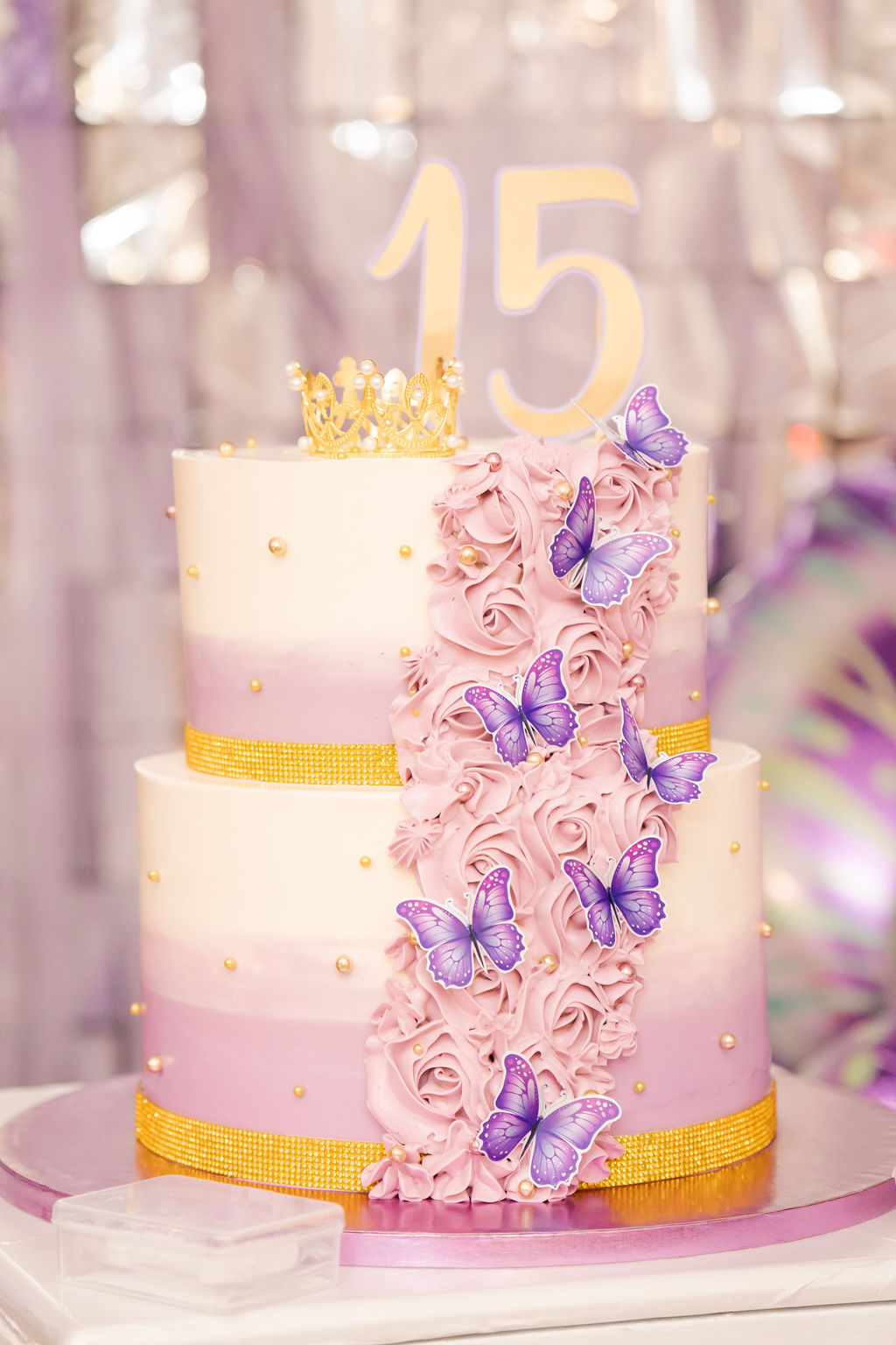 Tarta de quinceañera de tres pisos decorada con mariposas y rosas en tonos lila